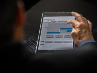 Ausbilderbildschirm des Simulators auf einem Tablet, mit einer Hand bei der Bedienung