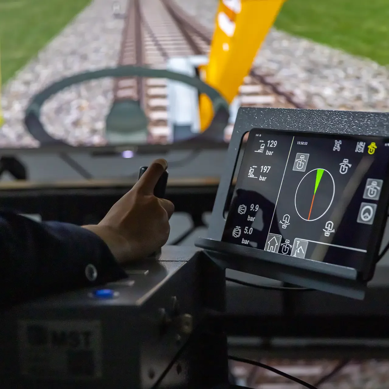 Hand am Simulator, im Hintergrund die Simulation auf einem Bildschirm