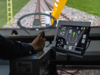 Hand am Simulator, im Hintergrund die Simulation auf einem Bildschirm